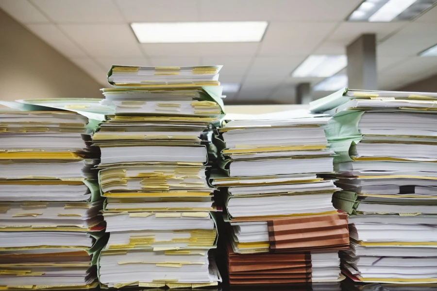 Huge piles of paperwork stacked up high on a desk
